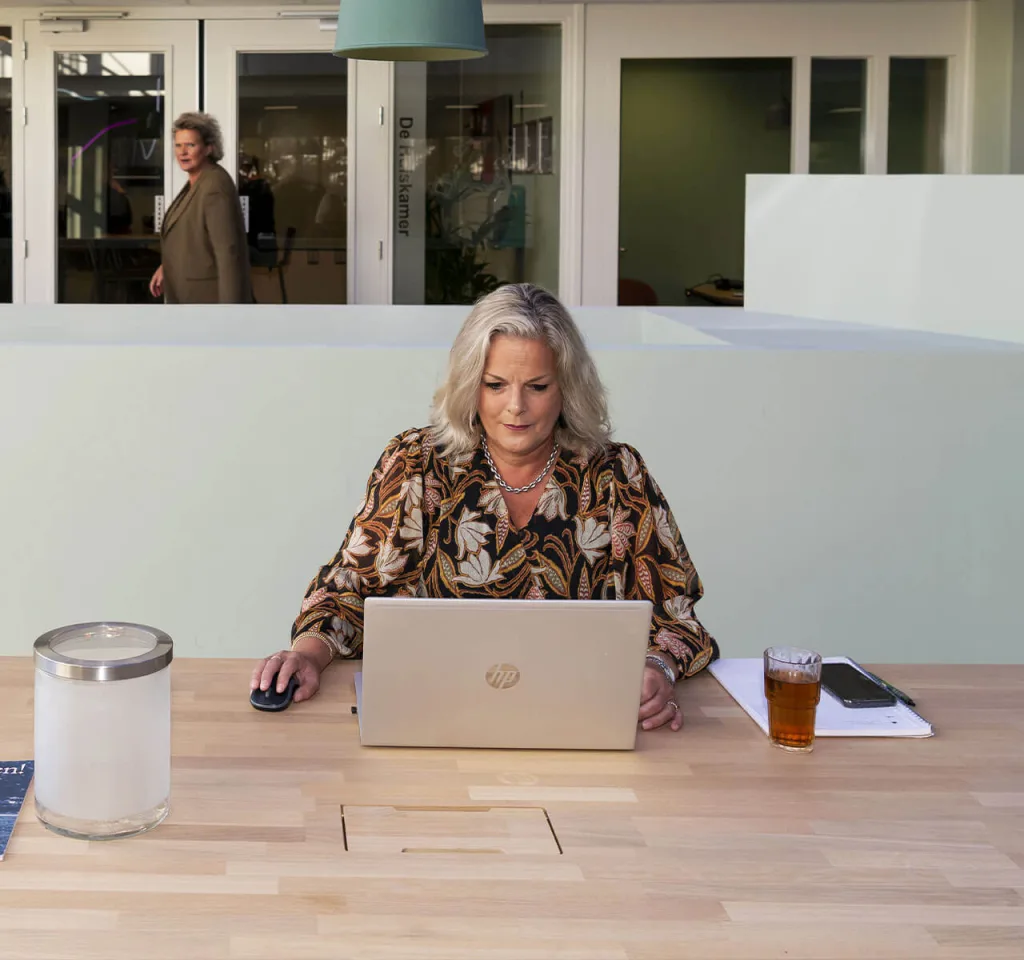 Een vrouwelijke medewerker werkt geconcentreerd achter haar bureau op kantoor